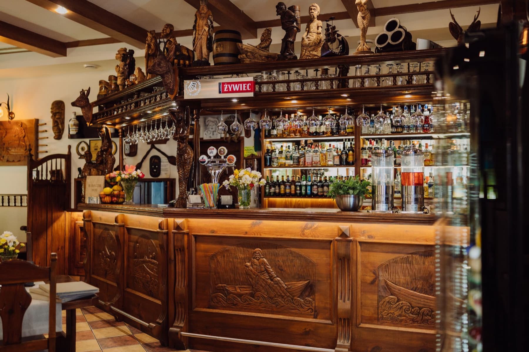 Rzeźbiony drewniany bar restauracji Kabaczek z figurami i butelkami
